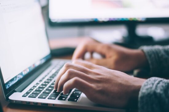 A photo of a person's hands on a keyboard of their laptop.