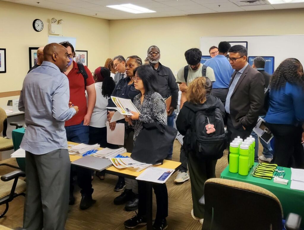 A photo of a busy room showing people talking to vendors at their table.